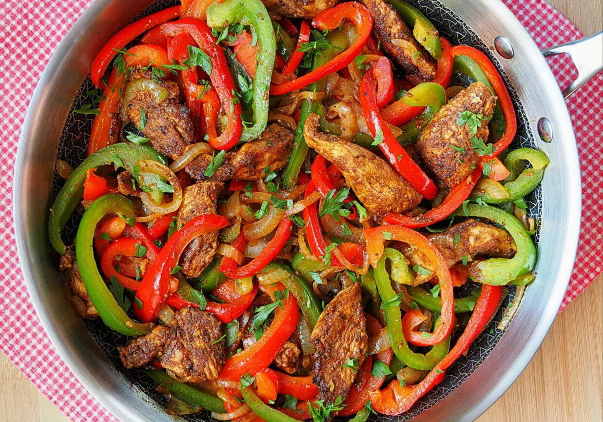 Kolorowe papryki i kurczak w przyprawach, gotowe do podania. Tak właśnie wyglądają pyszne fajitas co to za danie!