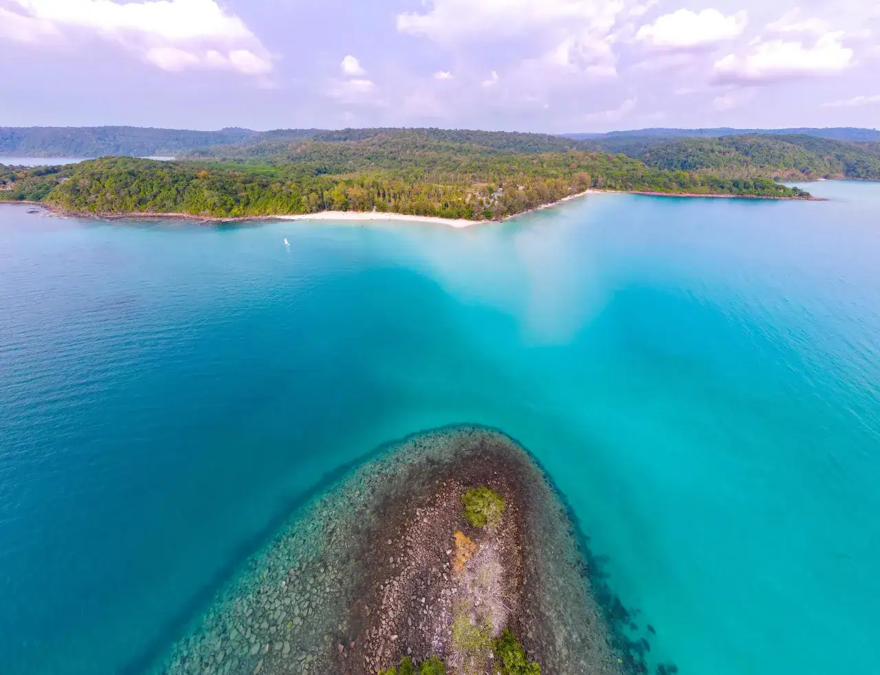 Rajska plaża z turkusową wodą i zielonymi wzgórzami, jak na Ko Phi Phi.