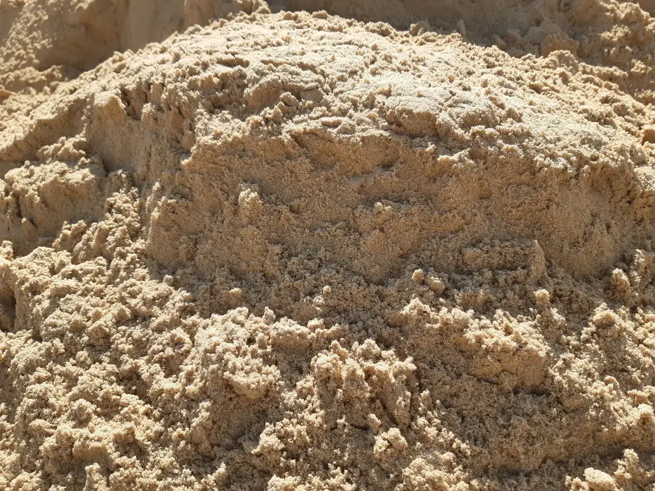 Zbliżenie na piasek budowlany. Zastanawiasz się, ile kosztuje tona piachu? Ten materiał jest kluczowy w budownictwie.