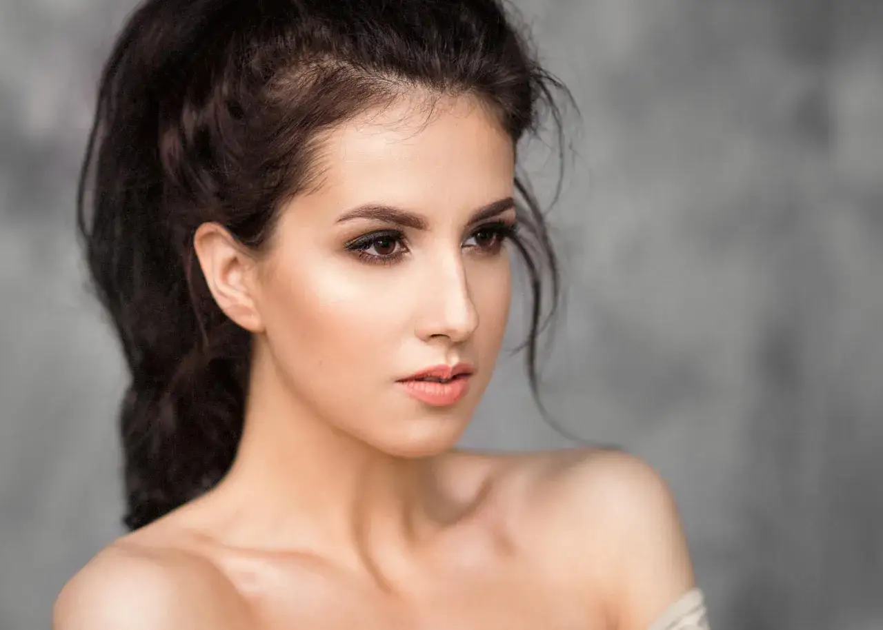 Portret kobiety z perfekcyjnym makijażem tfp. Delikatne cienie na powiekach i subtelny błyszczyk na ustach podkreślają jej urodę.
