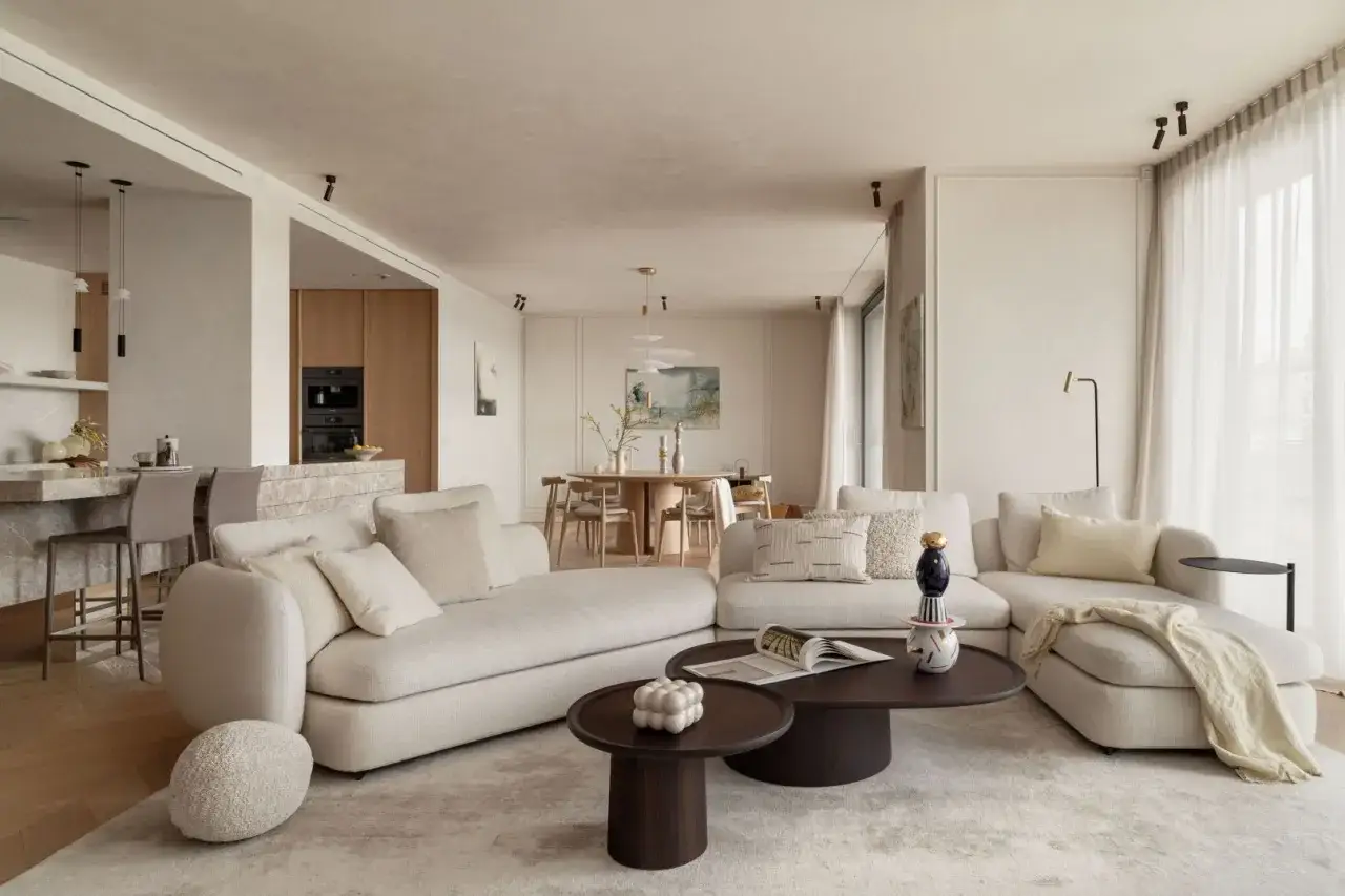 Piękne nowoczesne wnętrza: jasna, przestronna strefa dzienna z wygodną sofą, stolikami kawowymi i aneksem kuchennym.