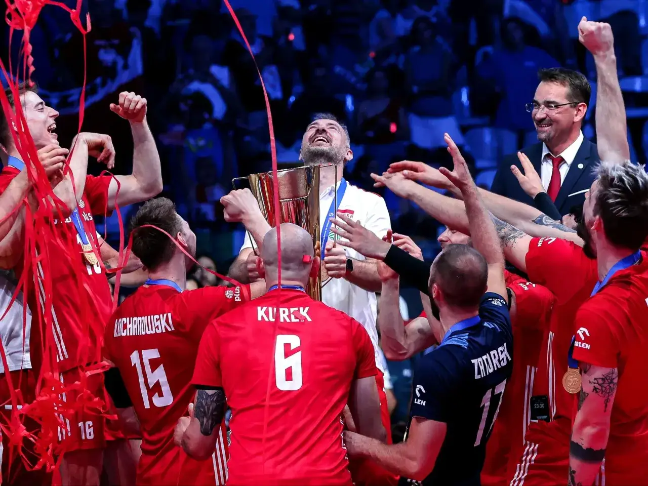 Polscy siatkarze świętują zwycięstwo, trzymając puchar. Ich radość widać na twarzach, a czerwone konfetti sypie się wokół. To moment chwały, który na zawsze zapisze się w historii mistrzostwa świata siatkówka tabela.