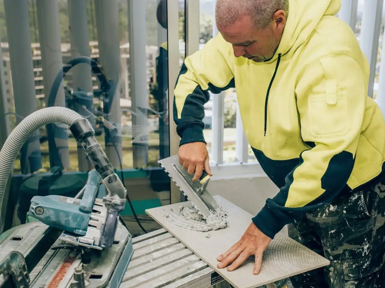 Płytkarz używa kielni do rozprowadzania zaprawy na płytce 120x60.