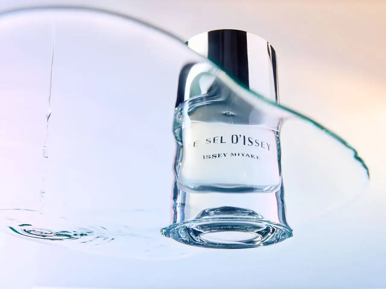 Woda toaletowa L'Eau d'Issey Miyake w szklanej butelce, otoczona wodą. Czy trwalsza woda toaletowa czy perfumowana?