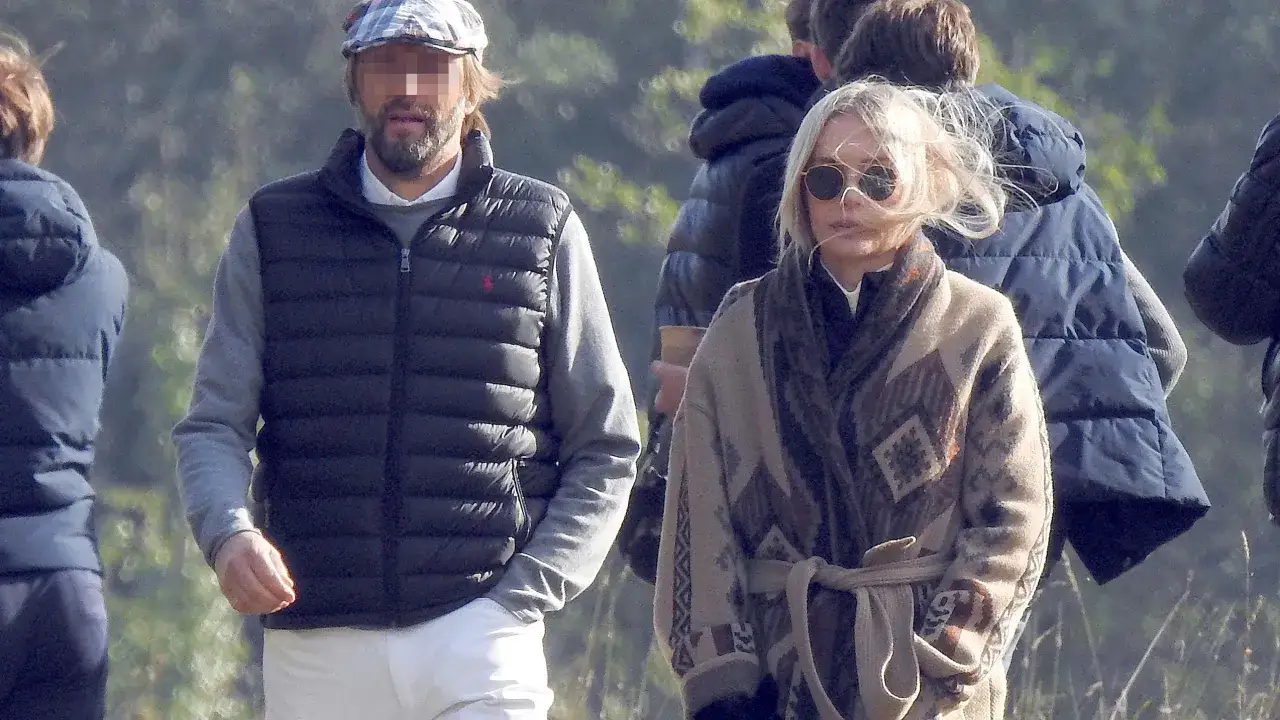 Agnieszka Woźniak-Starak z nowym partnerem spacerują. Ona w kolorowym kardiganie, on w kamizelce i czapce.