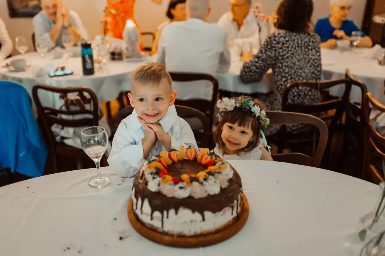 Dzieci z uśmiechem czekają na tort. Zastanawiasz się, ile trwają chrzciny?