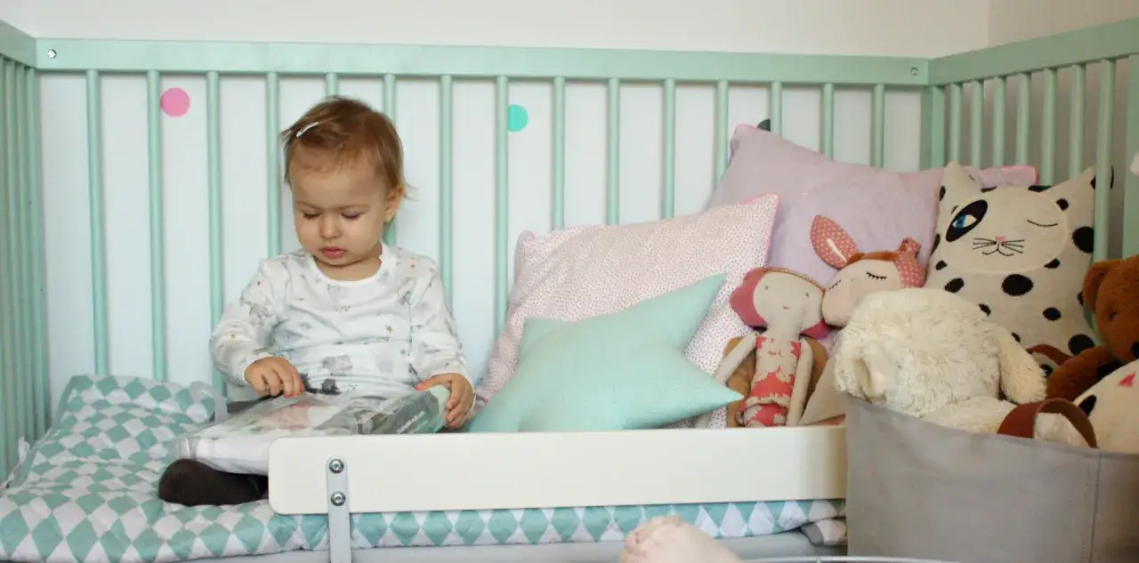 Uśmiechnięte roczne dziecko bawiące się w łóżeczku