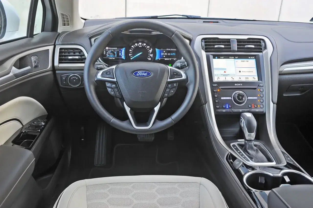 Wnętrze Forda Mondeo MK5: kierownica, deska rozdzielcza z ekranem dotykowym i nawigacją, dźwignia zmiany biegów.