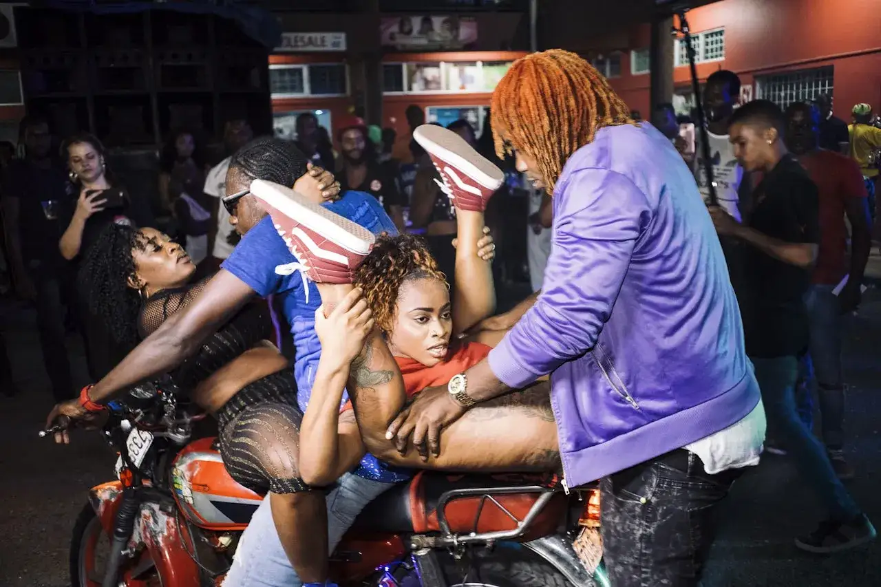 Tancerka na motocyklu, jej nogi uniesione w powietrzu, to esencja dancehall co to. Energetyczna nocna impreza.