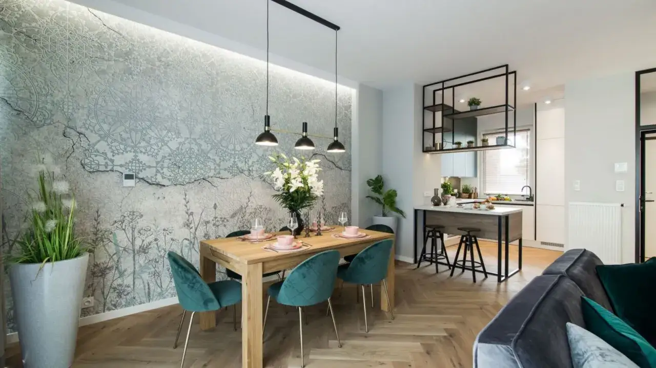 Jak dobrać lampy do salonu i jadalni? Stylowe oświetlenie nad drewnianym stołem i welurowe krzesła w odcieniu butelkowej zieleni.