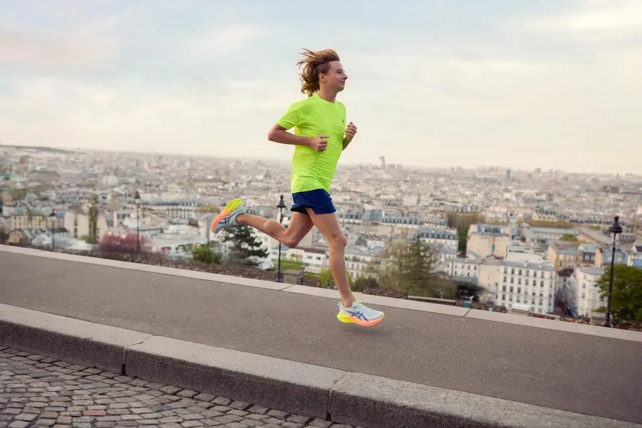 Młody biegacz w jaskrawej koszulce pokonuje trasę nad panoramą miasta. Zastanawiasz się, ile km biegać na początek? Zacznij od małych kroków!