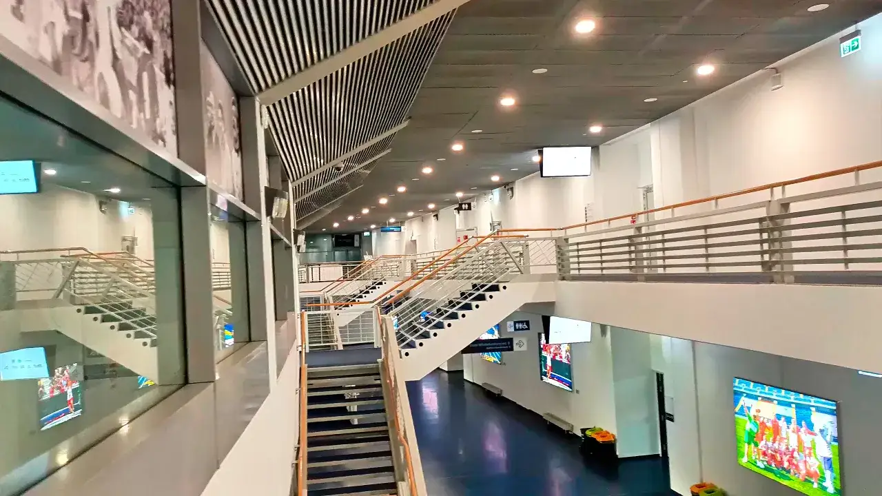 Wnętrze stadionu Śląskiego w Chorzowie. Widoczne schody, balustrady i ekrany z transmisjami.