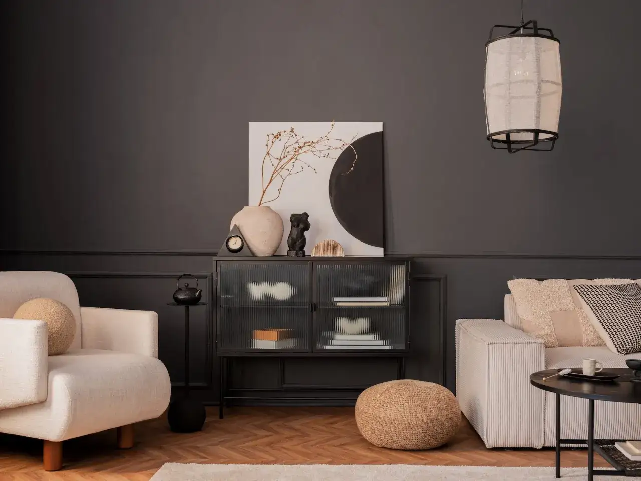 Inspiracja, jak pomalować salon: ciemne ściany, jasna kanapa i fotel, szklana witryna, sztuka.