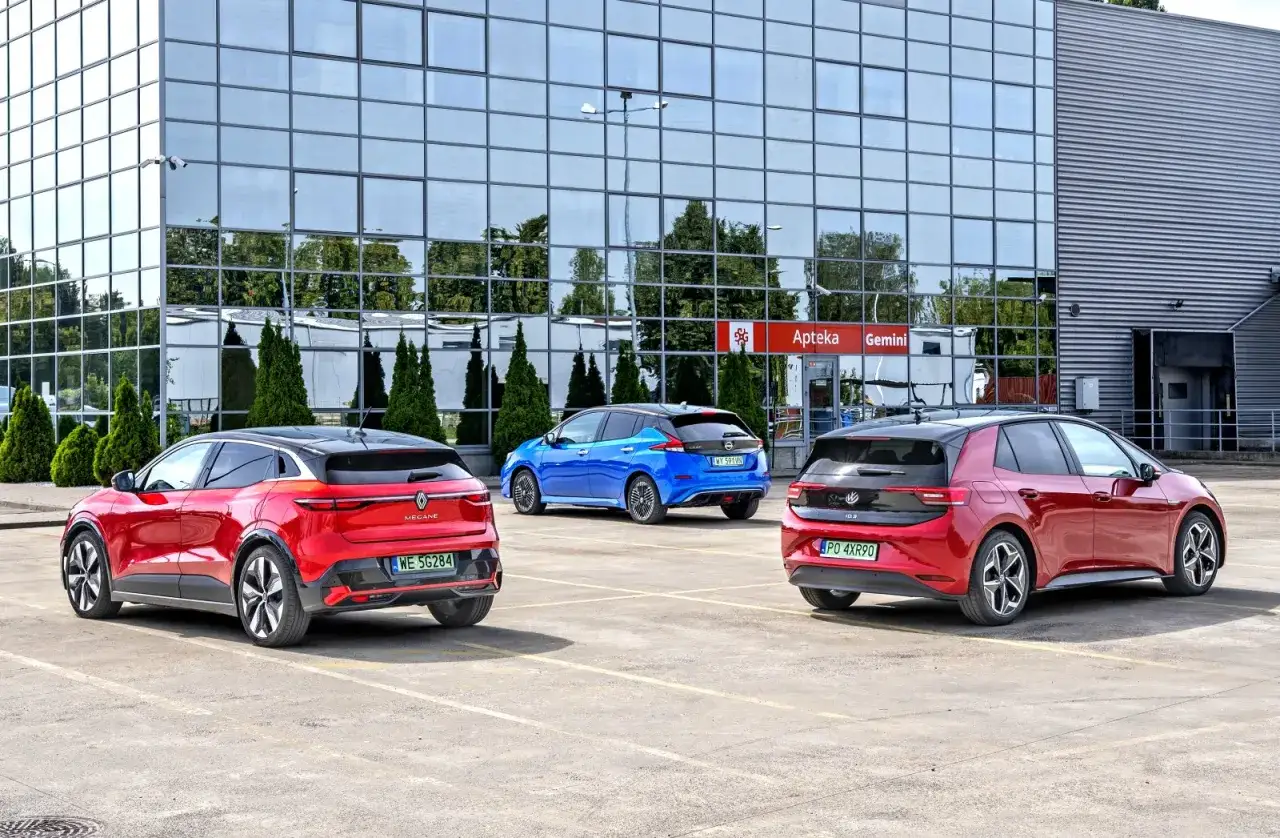 Trzy samochody elektryczne: czerwony Megane 3, niebieski Nissan Leaf i czerwony VW ID.3. Wymiary tych modeli są kluczowe dla wyboru.