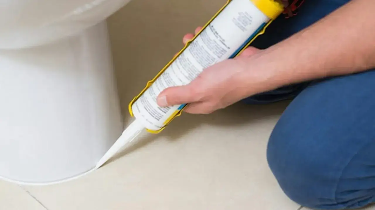 Nakładanie silikonu wokół toalety. Czy silikon można nakładać warstwami? Tak, ale najlepiej zrobić to jednorazowo, by uniknąć widocznych łączeń.