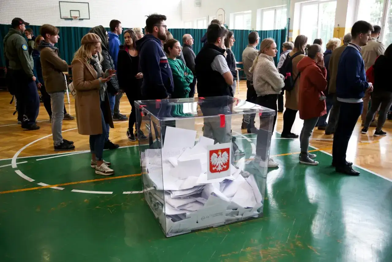 Ludzie stoją w kolejce do urny wyborczej. Przezroczysta skrzynka wypełniona jest kartami do głosowania, co symbolizuje obywatelską kontrolę wyborów.