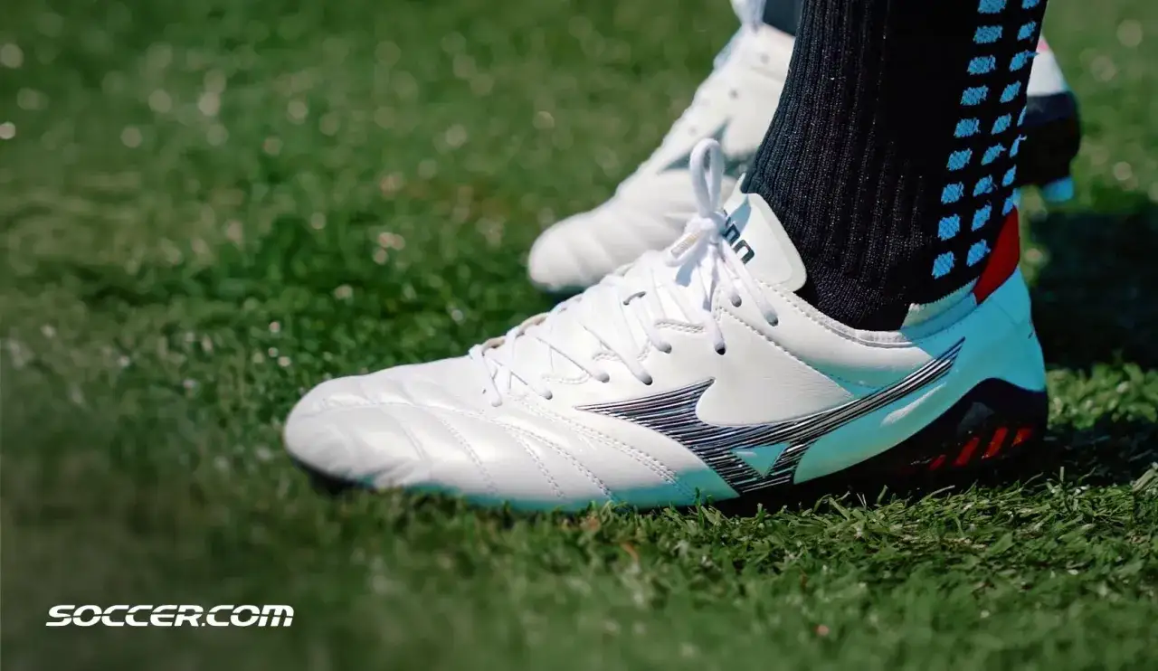 Piłkarskie buty Mizuno na zielonej murawie. Mizuno to znana firma produkująca sprzęt sportowy.