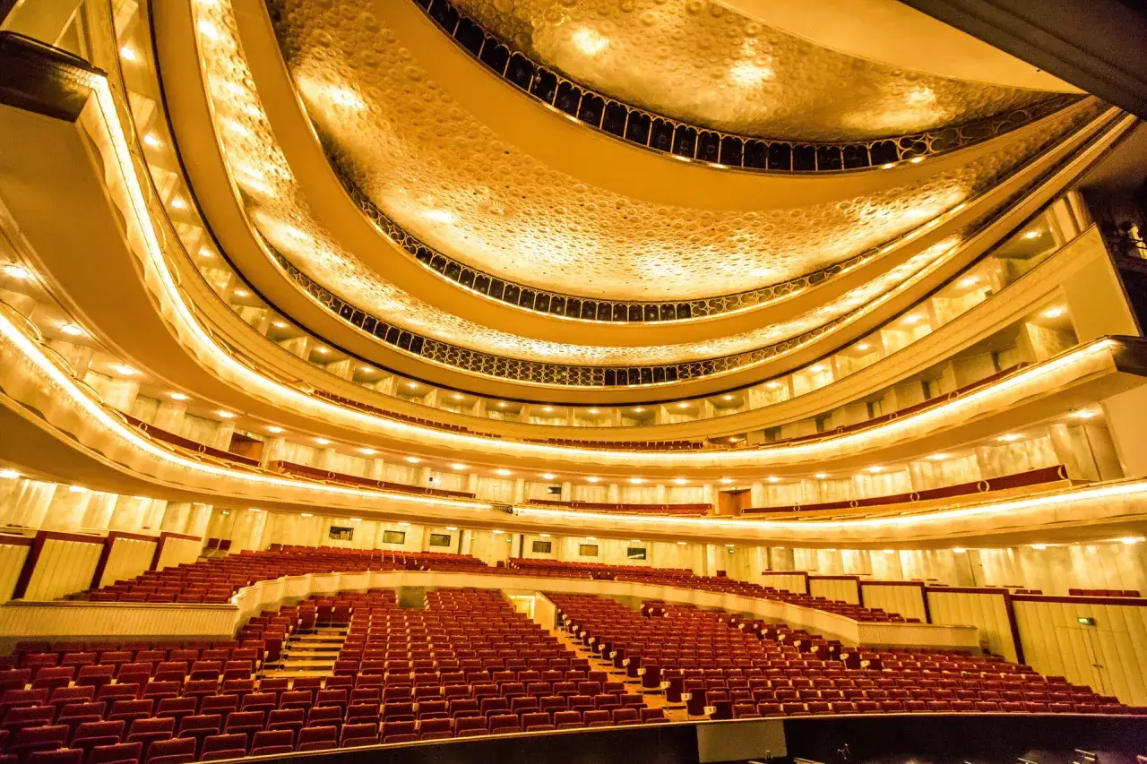 Wielki teatr, plan widowni z rzędami czerwonych foteli i złoconym sufitem.