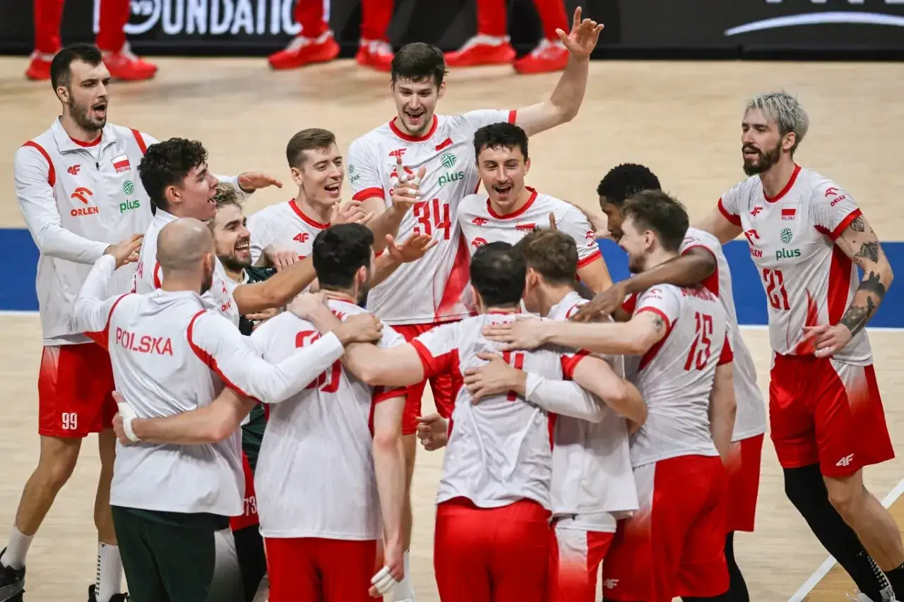 Drużyna siatkarzy świętuje zwycięstwo. Ich radość widać na twarzach, a biało-czerwone stroje symbolizują Polskę. To moment, który może wpłynąć na mistrzostwa świata siatkówka tabela.