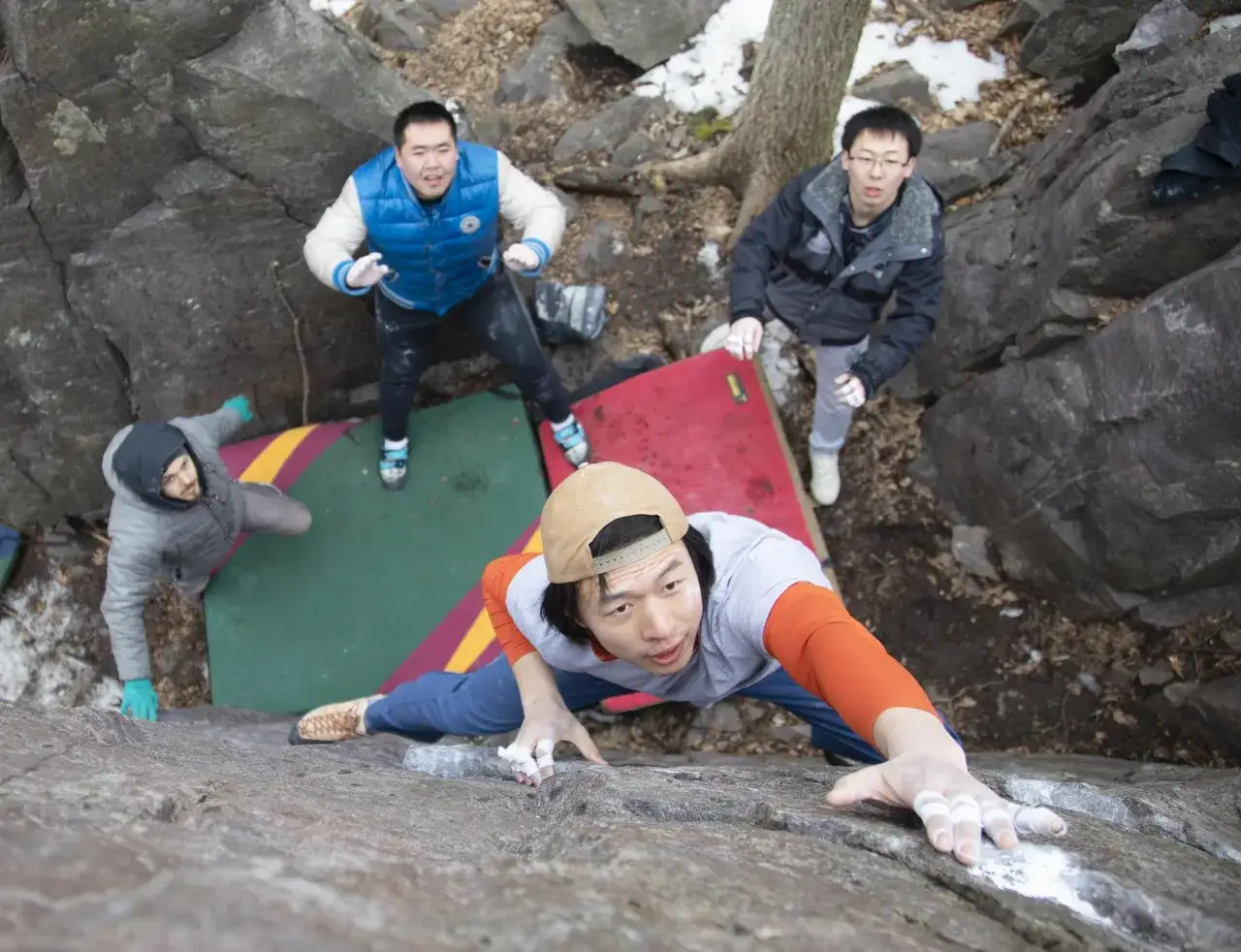 Grupa przyjaciół ćwiczy różne rodzaje wspinaczki, w tym bouldering, na skalnym terenie.
