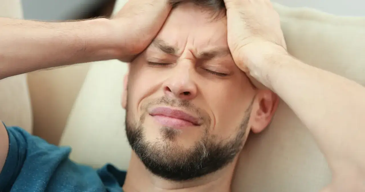 osoba z bólem głowy lub brzucha, trzymająca się za skronie