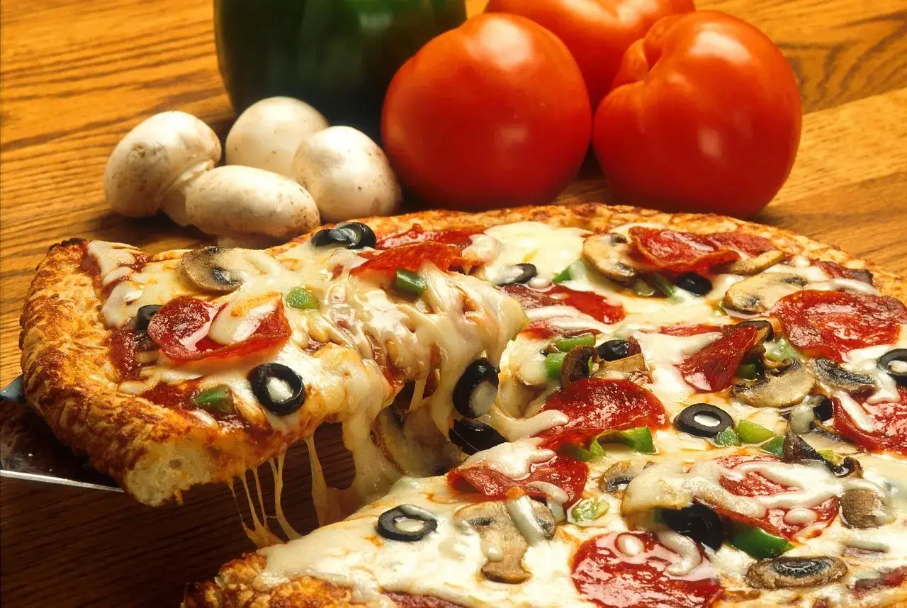 Pyszna pizza z serem, pepperoni, pieczarkami i oliwkami. Idealne dodatki, by dowiedzieć się, jakie zioła do pizzy wybrać.
