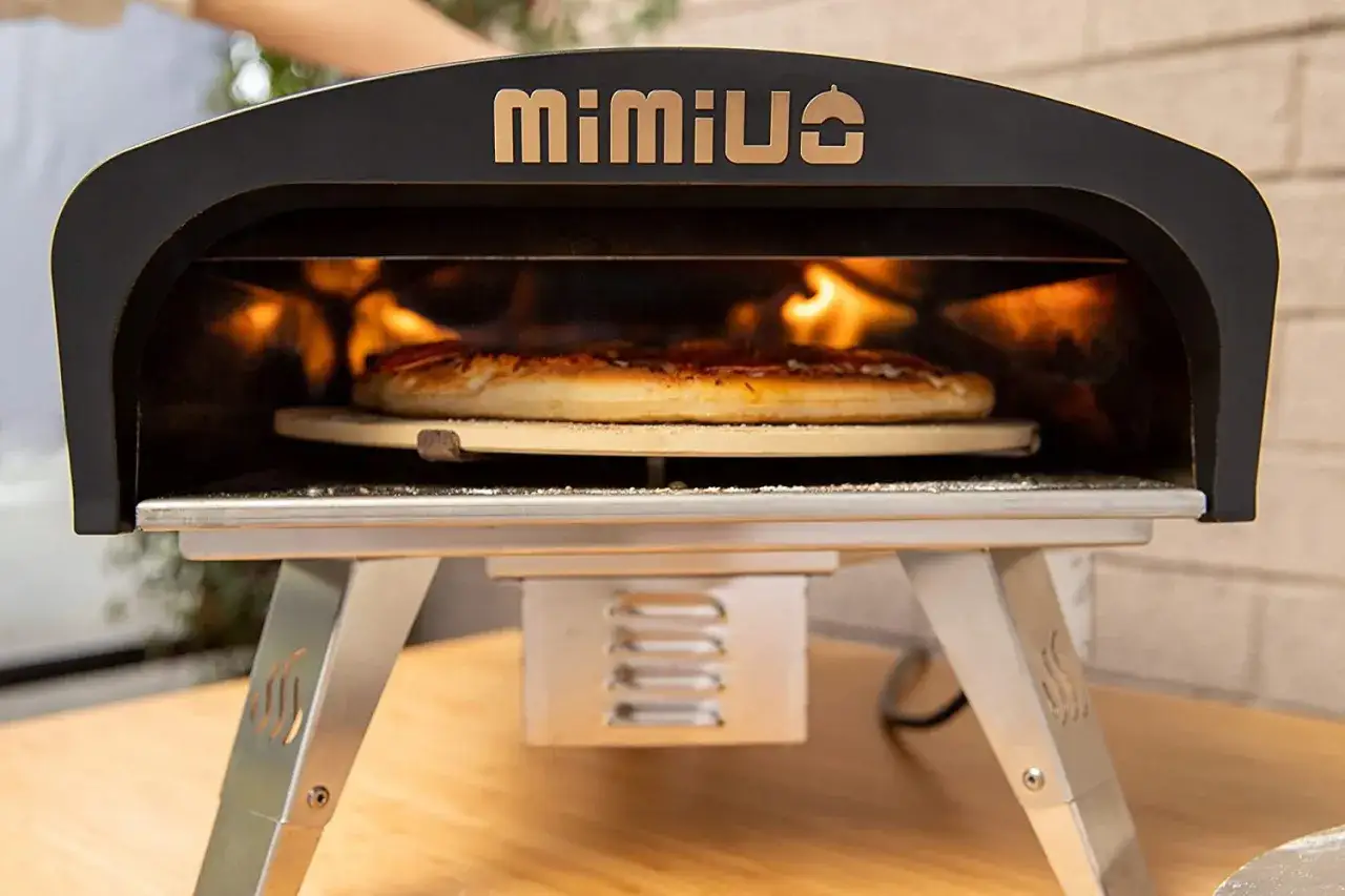 Piec do pizzy gazowy MIMIUO z płonącym ogniem w środku, na kamieniu piecze się pizza.