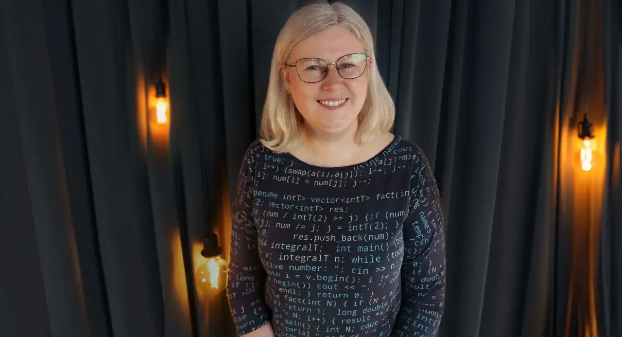 Kobieta w okularach w bluzce z kodem programistycznym. Wykształcenie średnie otwiera drzwi do kariery w IT.