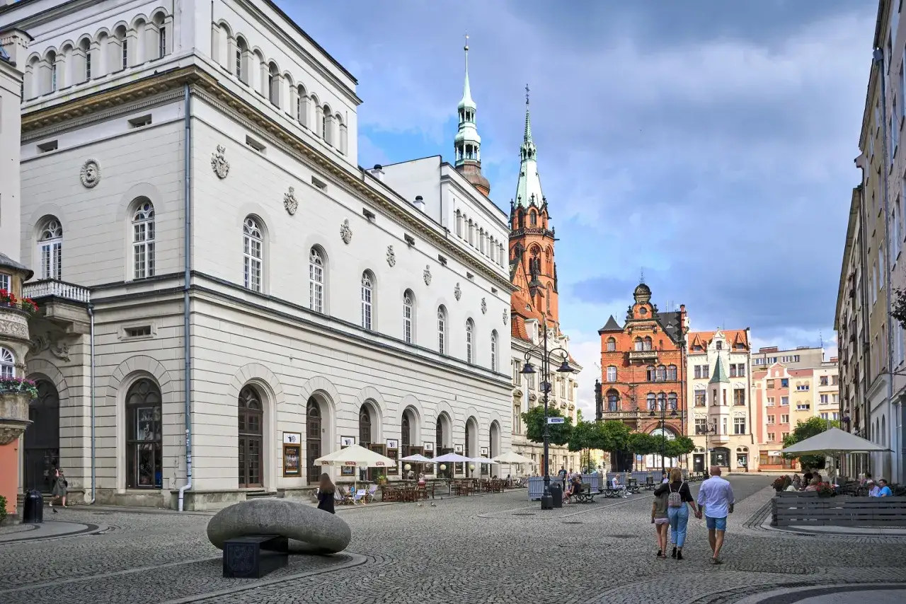 Rynek w Legnicy z pięknymi kamienicami i wieżami kościelnymi. Wiele atrakcji czeka na odkrycie w tym urokliwym mieście.