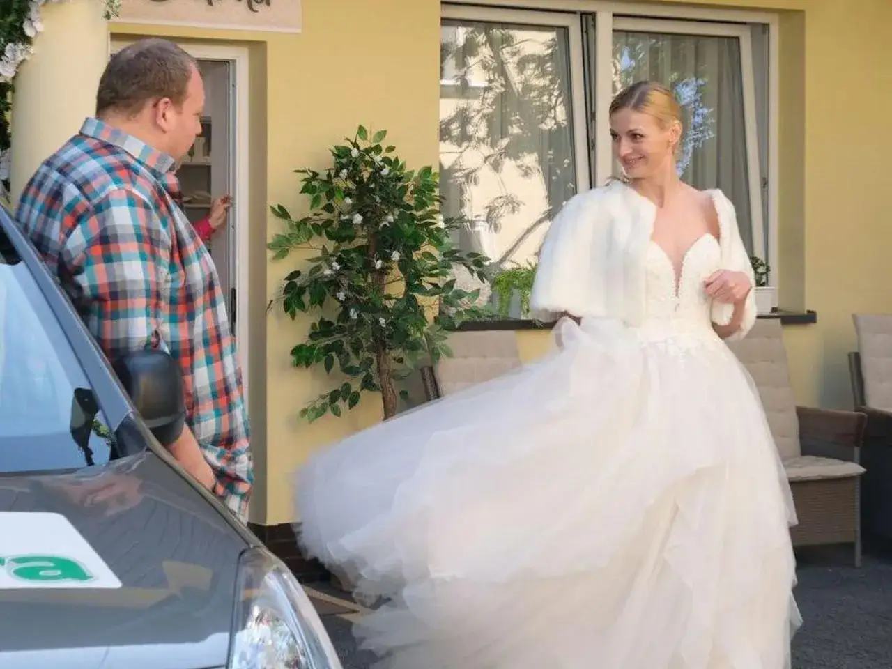 Panna młoda w sukni ślubnej i mężczyzna w kratę rozmawiają przed domem. Czy to zapowiedź tego, co się wydarzy w M jak miłość?