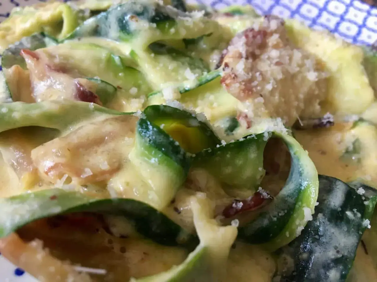 Kremowa carbonara z cukinii, z kawałkami boczku i posypana parmezanem. Pyszne danie, które zachwyca smakiem.