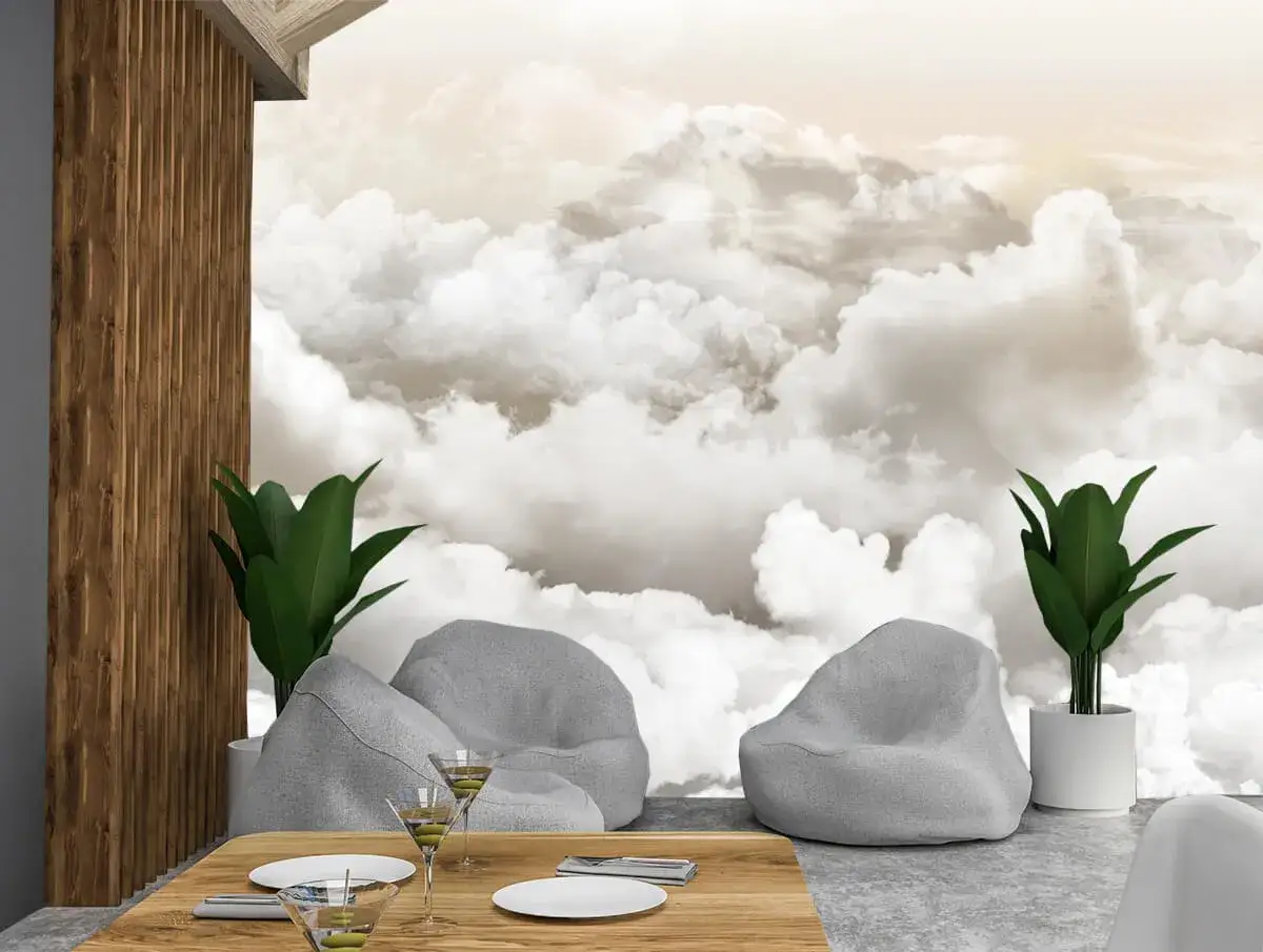 Inspiracja na to, jak namalować chmury na ścianie: przytulne fotele, st&oacute;ł z kieliszkami i rośliny na tle nieba.