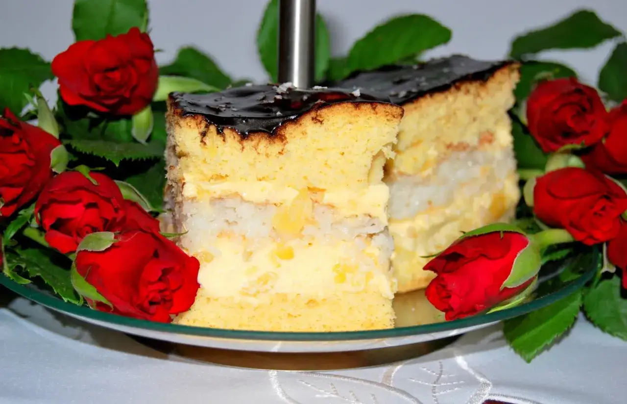 Pyszne ciasto z ananasem z puszki i budyniem, ozdobione czerwonymi r&oacute;żami. Idealne na specjalną okazję.