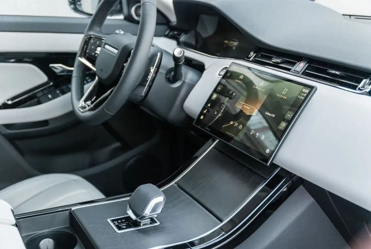 Wnętrze Land Rover Evoque z nowoczesnym ekranem dotykowym, kierownicą i dźwignią zmiany bieg&oacute;w.