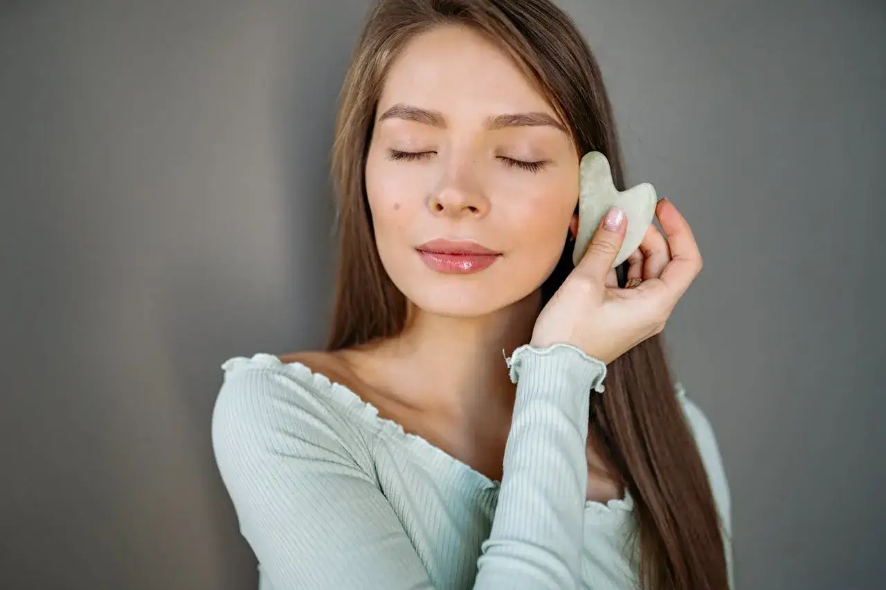 kobieta wykonująca poranny masaż gua sha na twarzy