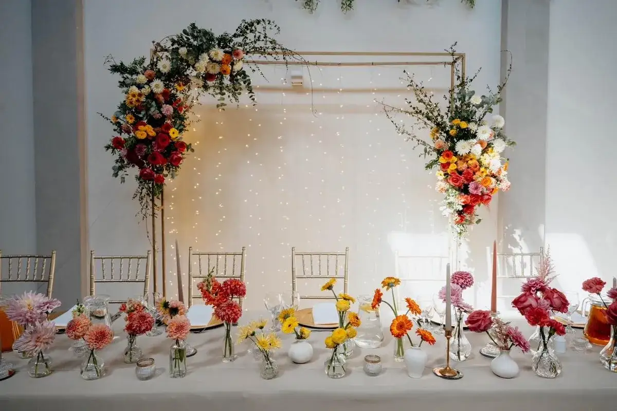 St&oacute;ł weselny ozdobiony bujnymi, kolorowymi kwiatami i delikatnymi światełkami. Inspiracja dla tych, kt&oacute;rzy chcą wiedzieć, jak zostać florystą.