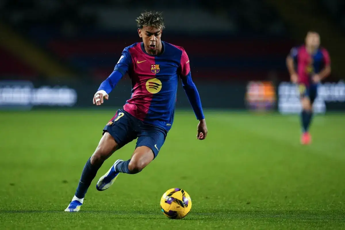 Młody piłkarz FC Barcelony w akcji, z piłką przy nodze.