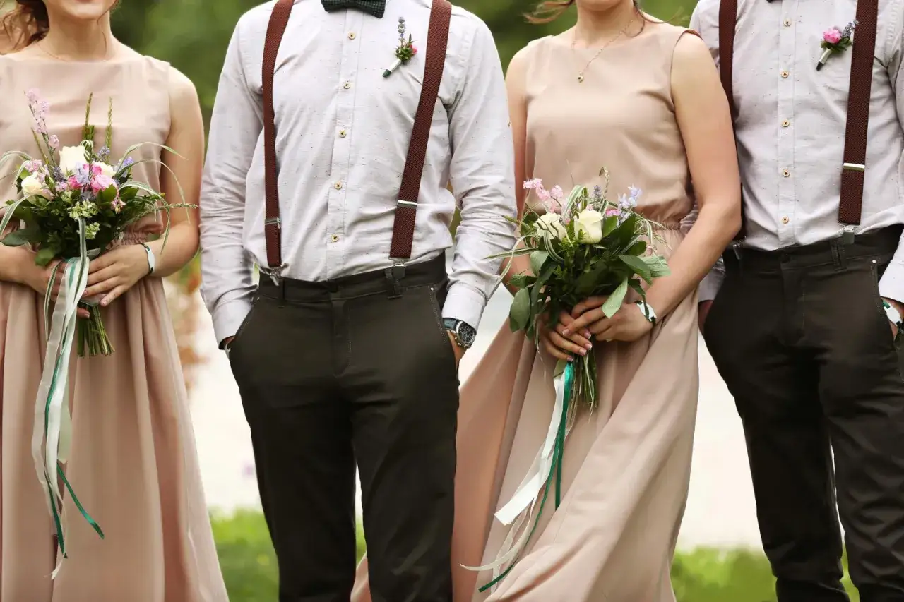 Eleganckie stylizacje na wesele: panie w beżowych sukniach z bukietami, panowie w koszulach, szelkach i ciemnych spodniach.