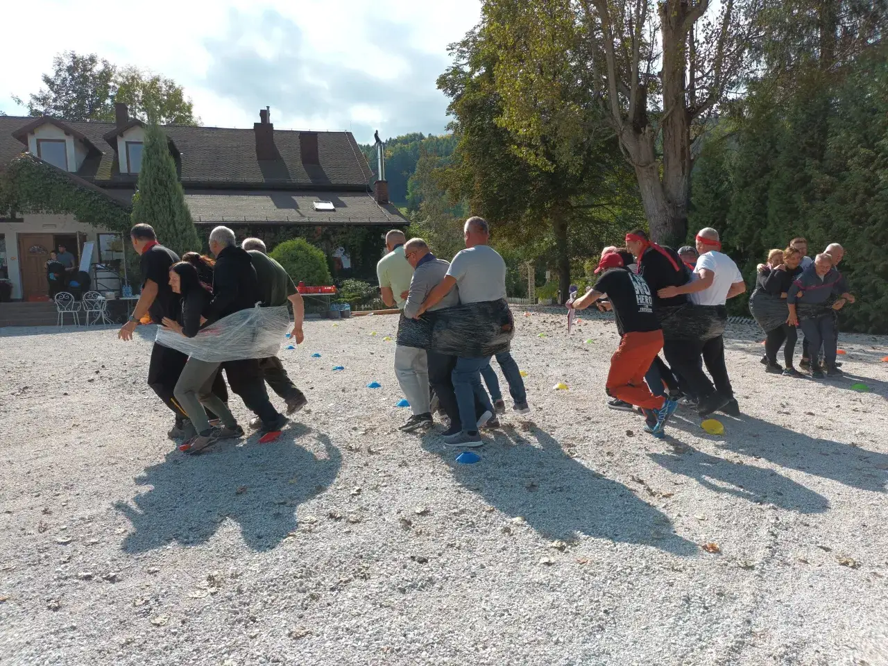 Grupa młodzieży bierze udział w kreatywnych zabawach, próbując poruszać się razem, owinięci folią.