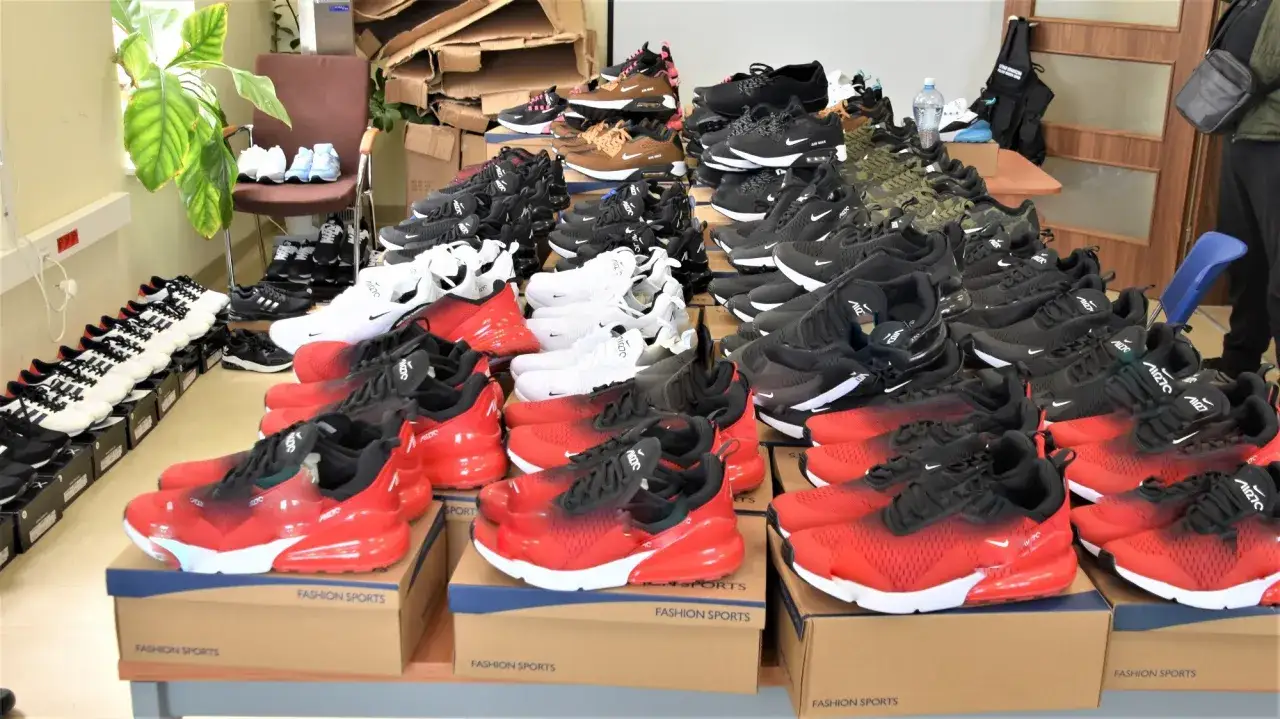 Stosy butów sportowych, w tym czerwonych i czarnych Nike Air Max, białych i czarnych Adidas. Czy to świeże buty, czy oryginalne?