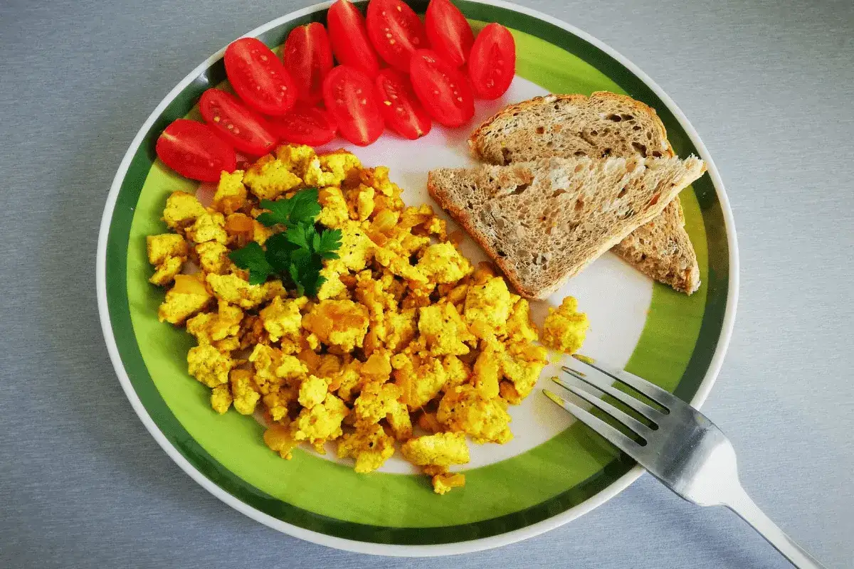 Jajecznica z tofu to świetny spos&oacute;b, czym zastąpić jajka w diecie wegańskiej. Podana z pomidorkami i grzankami.