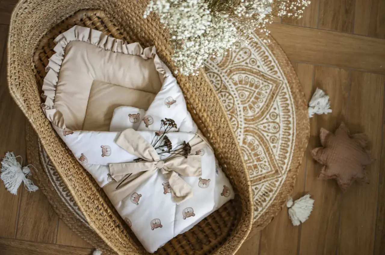 Uroczy rożek niemowlęcy w misie, zawinięty w koszu wiklinowym, ozdobiony suszonymi kwiatami i wstążką.
