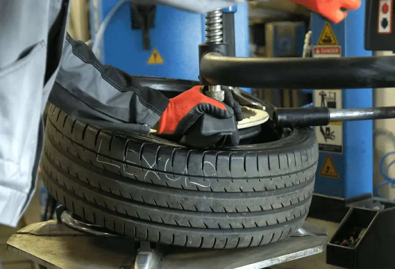 Mechanik w rękawiczkach naprawia oponę. Zastanawiasz się, ile kosztuje łatanie opony?