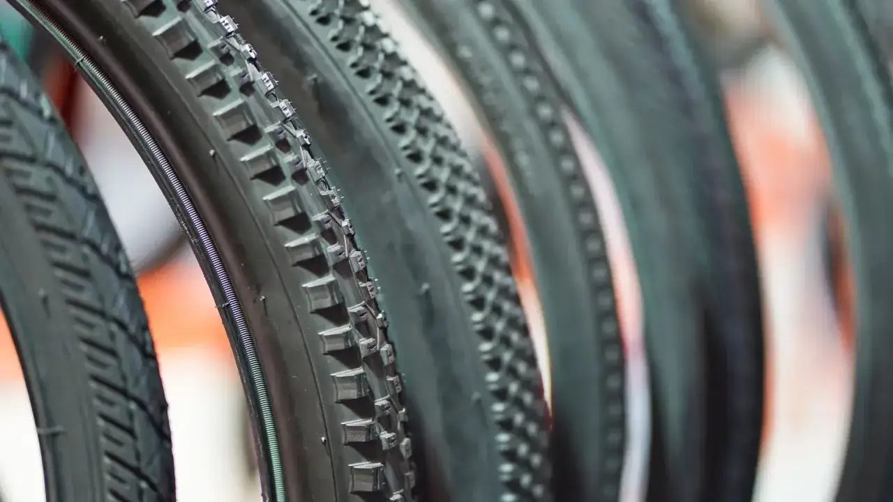 Rzędy opon rowerowych, niekt&oacute;re z widocznym drutem, inne zwijane, gotowe na przygodę.