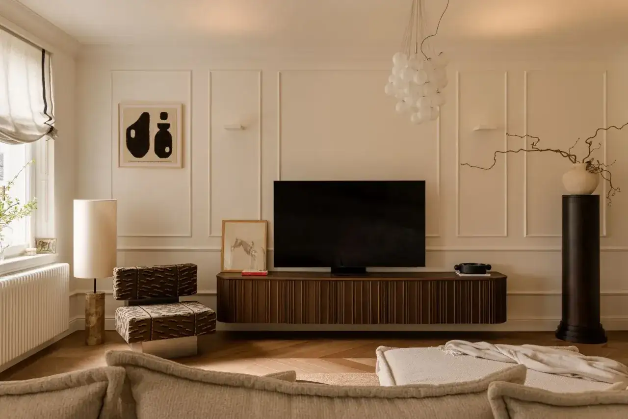 Eleganckie mieszkanie w stylu paryskim z wygodną kanapą, designerskim fotelem i nowoczesnym telewizorem na drewnianej szafce.
