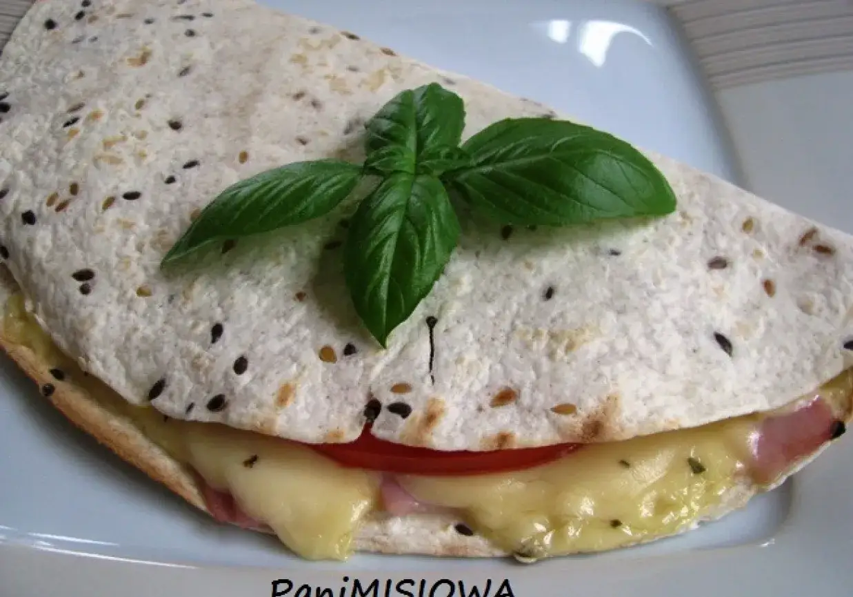 Pyszna tortilla z szynką i serem na ciepło, z pomidorem i bazylią, idealna na szybki posiłek.