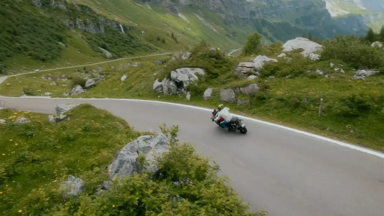 Motocykl na alpejskiej przełęczy z widokiem na g&oacute;ry