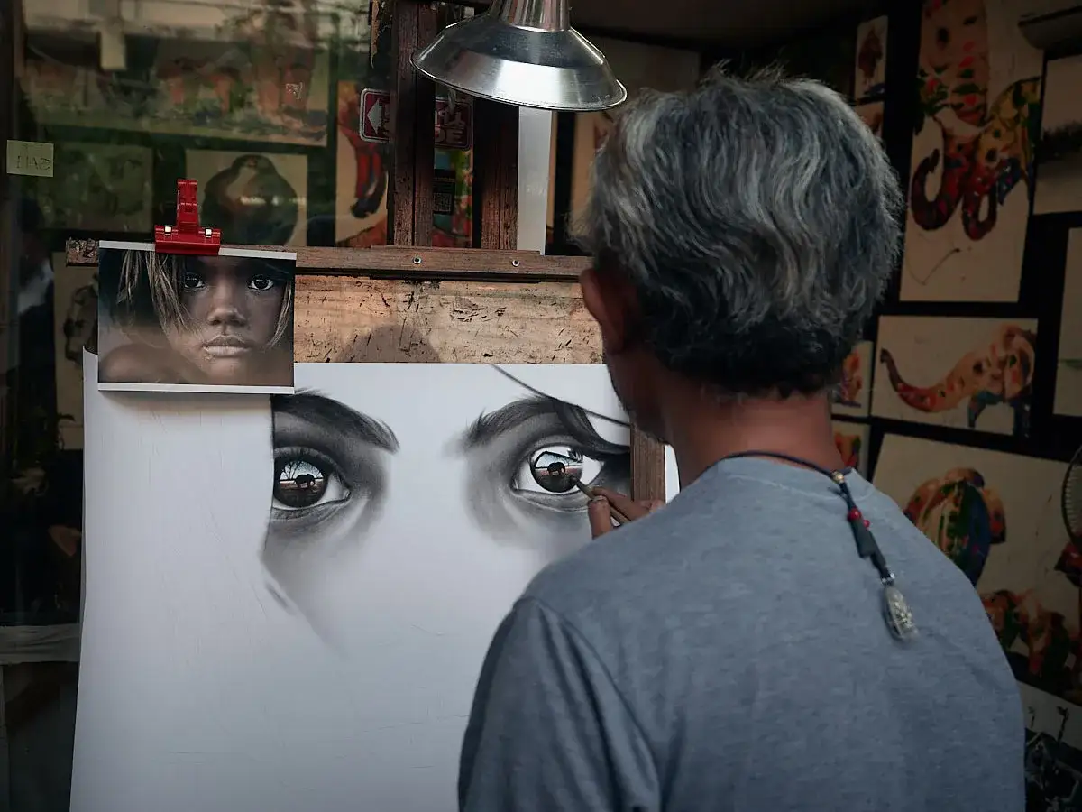 Artysta tworzy kreatywne zdjęcia, szkicując portret dziewczynki. W jej oczach odbija się krajobraz.