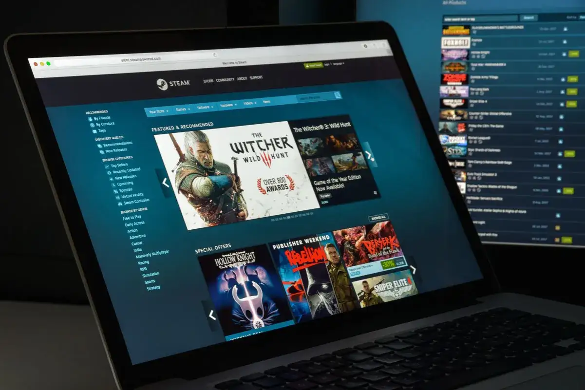 Laptop z otwartą stroną Steam, prezentującą gry jak 