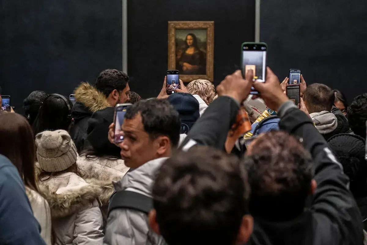 Tłum ludzi robi zdjęcia Mona Lisie. Trudno ocenić, ile eksponatów jest w Luwrze, ale ten jest popularny.